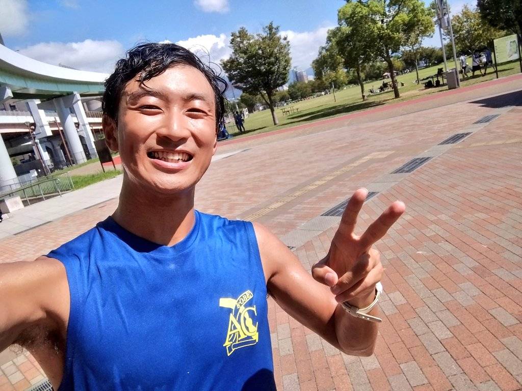 KOBE AC の青いランニングシャツを着た選手が公園で笑顔のセルフィー。