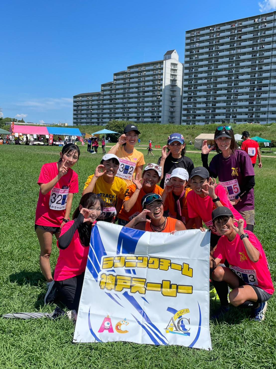 女性メンバーが「ランニングチーム 神戸えーしー」のバナーを持って笑顔で並ぶ。