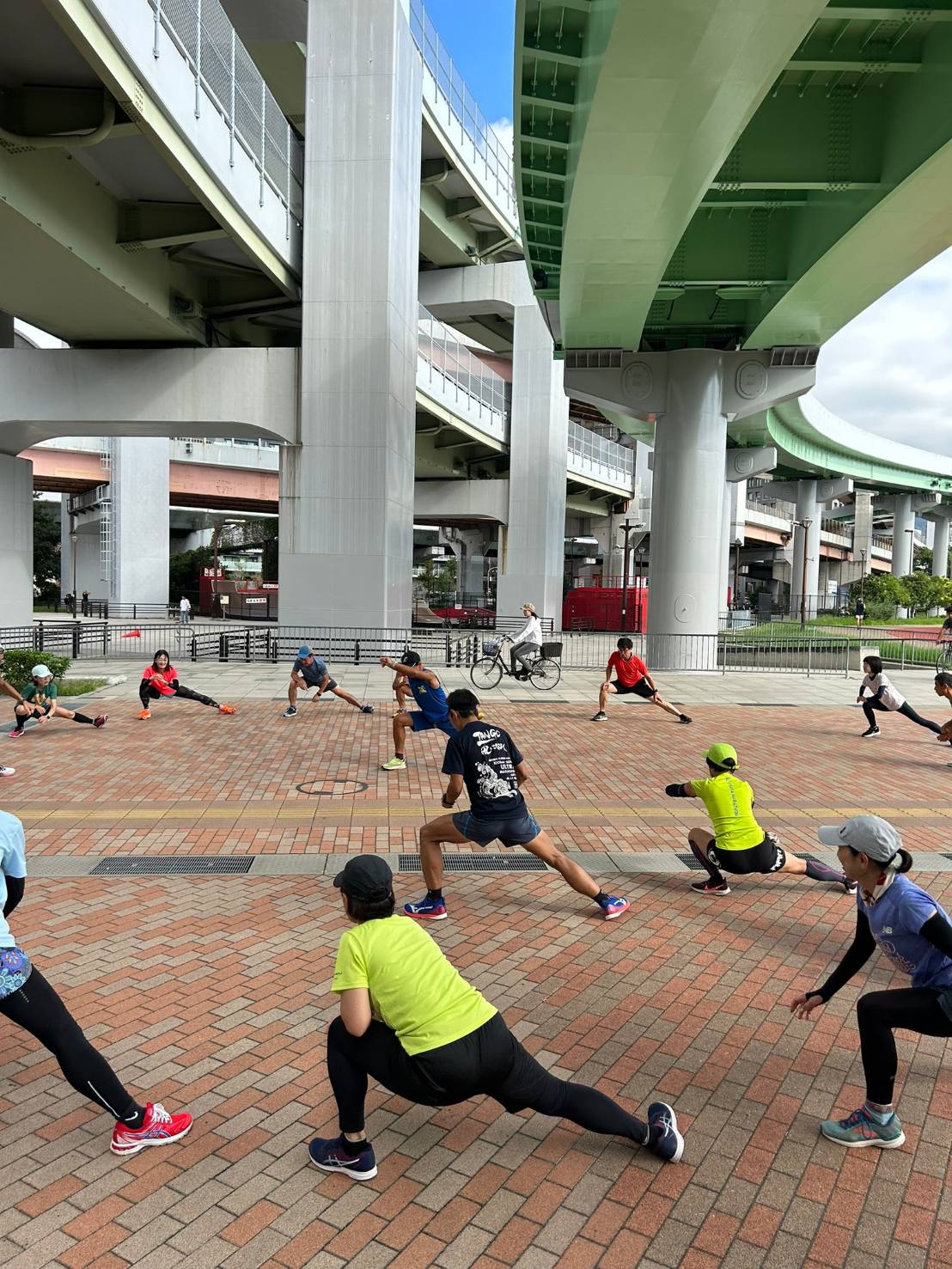 高架下でストレッチをする神戸えーしーのメンバー。