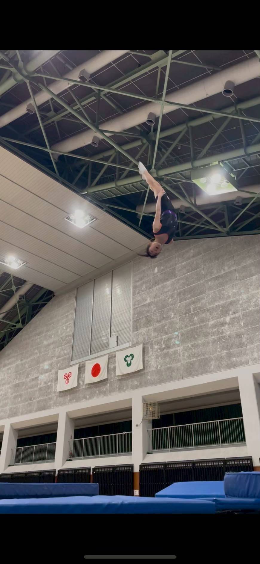 国旗を背に空中で回転する選手
